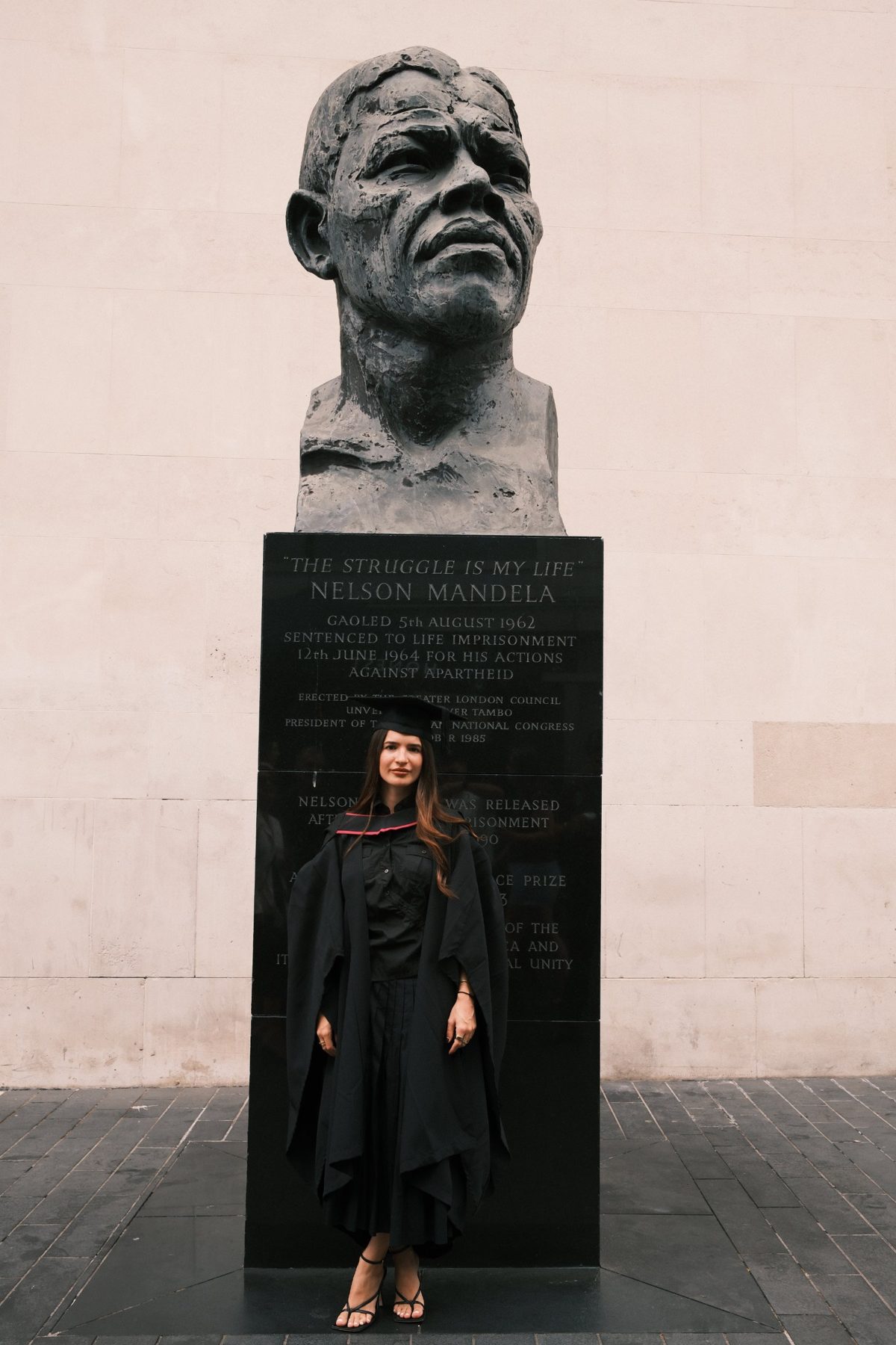 Gia in her graduation gown in front of the Nelson Mandela bust on London's South Bank